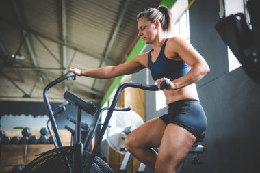 Spor salonunda eliptik bir bisiklette egzersiz yapan bir kadın fitness modeli.