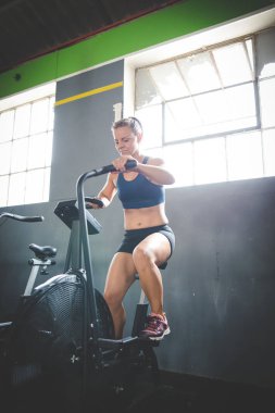 Spor salonunda eliptik bir bisiklette egzersiz yapan bir kadın fitness modeli.