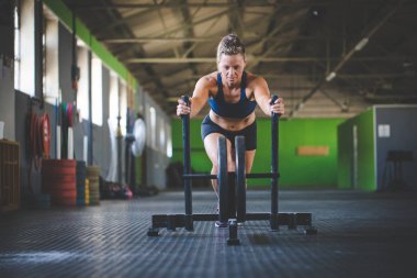 Hatun spor salonunda kızağı iten fitness modeli..