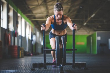 Hatun spor salonunda kızağı iten fitness modeli..
