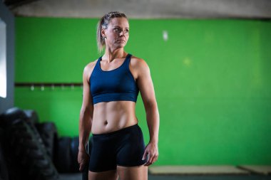 Spor salonunda çekiçle çapraz egzersiz yapan kadın fitness modeli.