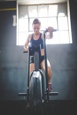 Spor salonunda eliptik bir bisiklette egzersiz yapan bir kadın fitness modeli.