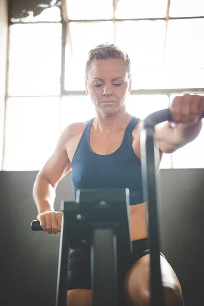 Female fitness model exercising on an elliptical training bike in a gym