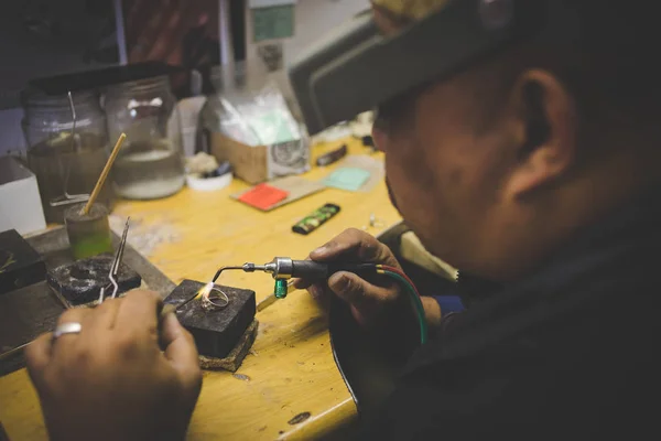 Close up image of a jeweler making jewelry with traditional hand tools in a jewelry shop.