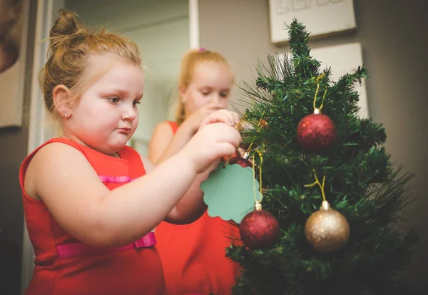 Image rapprochée de deux jeunes filles / sœurs, décorant un sapin de Noël pour les vacances — Photo