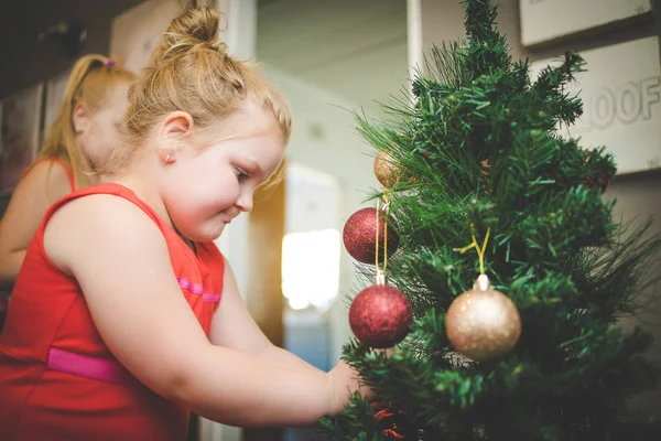 Image rapprochée de deux jeunes filles / sœurs, décorant un sapin de Noël pour les vacances — Photo