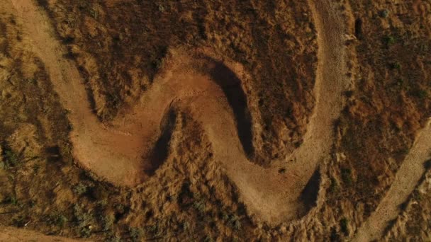 日没時の草原の乾燥ロードを車でサイクリストの空中写真 — ストック動画