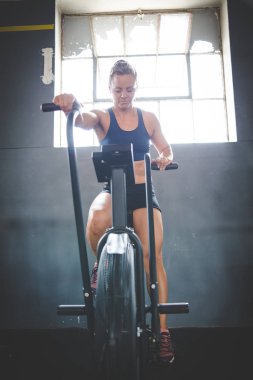 Spor salonunda eliptik bir bisiklette egzersiz yapan bir kadın fitness modeli.