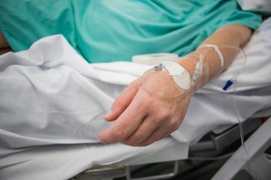 Bir doktorun hasta bir hastanın koluna damardan damar yolu açtığı görüntüyü kapat.