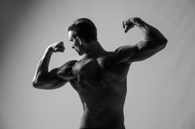 Stüdyoda vücudunu esneten bir erkek fitness modelinin yakın plan görüntüsü.