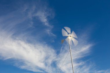 Güney Afrika 'nın batısındaki Karoo Burnu' nda bir çiftliğin elektrik tesisatının pillerini şarj eden dönen rüzgar türbininin geniş açılı görüntüsünü kapatın.