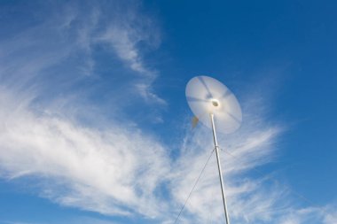 Güney Afrika 'nın batısındaki Karoo Burnu' nda bir çiftliğin elektrik tesisatının pillerini şarj eden dönen rüzgar türbininin geniş açılı görüntüsünü kapatın.