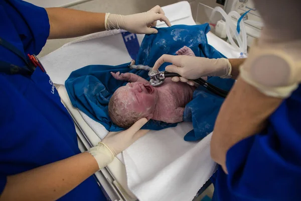 Close up image of a newly born, covered in vernix baby in a hospital