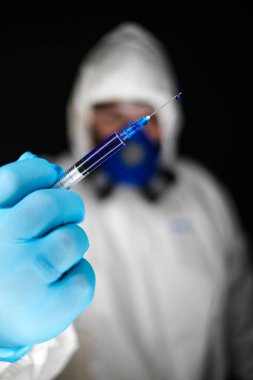 Tehlikeli virüsler için aşılarla çalışan koruyucu giysiler ve maskeler giyen bir sağlık çalışanının portre resmini kapatın.