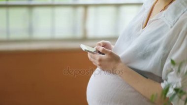 Akıllı telefon kullanan hamile bir kadın.