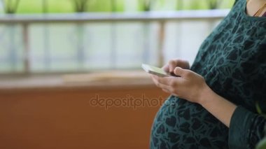 Akıllı telefon kullanan hamile bir kadın.