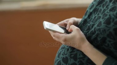 Akıllı telefon kullanan hamile bir kadın.
