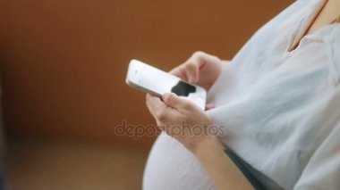 Akıllı telefon kullanan hamile bir kadın.