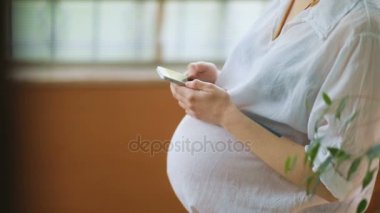 Akıllı telefon kullanan hamile bir kadın.