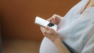 Akıllı telefon kullanan hamile bir kadın.