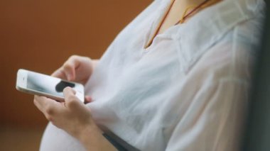 Akıllı telefon kullanan hamile bir kadın.