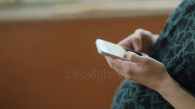Akıllı telefon kullanan hamile bir kadın.