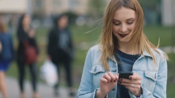 Frau schreibt SMS per Smartphone im Park — Stockvideo