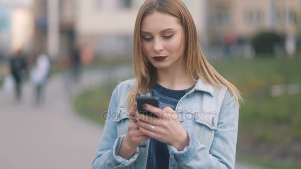 Kvinna textning via smartphone i parken — Stockvideo