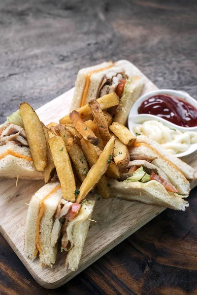 木の板にフライド ポテトと古典的なクラブ サンドイッチ — ストック写真