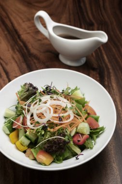 Taze organik vejetaryen sebze salatası ve ahşap masada salata sosu.