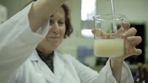 ビーカーで濁った液体を攪拌の女性 — ストック動画