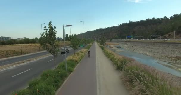 Drone Wide Ditembak Pengendara Sepeda Jalur Sepeda Tepi Sungai Perkotaan Stok Video Bebas Royalti