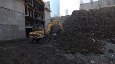 Ekskavatör koyu toprak ve moloz bir inşaatta kürekler