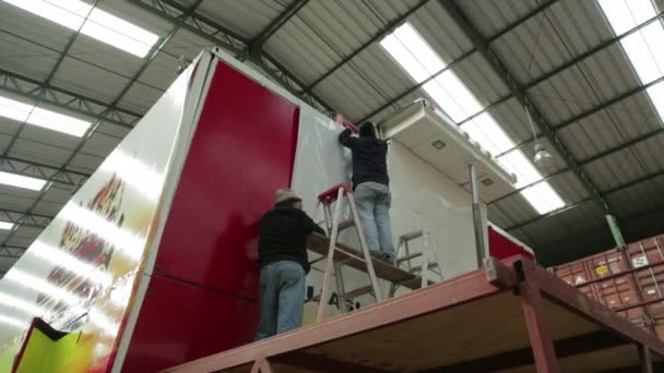 Workers applying vinyl to flat surface — Stock Video