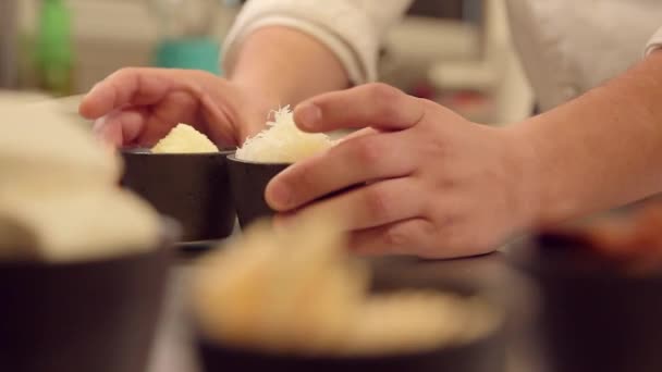 Mãos colocando uma tigela de queijos desfiados — Vídeo de Stock