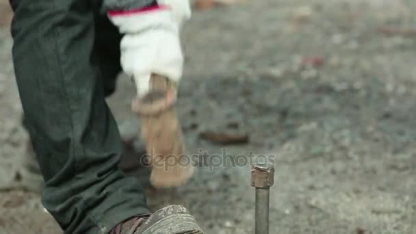 Ein Arbeiter hämmert eine Stange in den Boden — Stockvideo