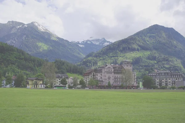 Krajobraz Interlaken z zielonym polem, budynkami i Alpami alpejskimi — Zdjęcie stockowe