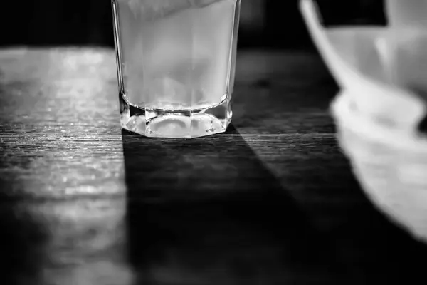 Slices of bread in the basket and glass of lemonade with blurred wooden table background. Black and white. — Stock Photo, Image