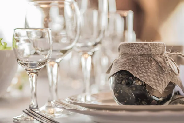 Bir düğün kutlama güzel rahat Restoran rustik Tablo ayarı. Kadehlerin, tabak ve gıda bir tablo. Konuklar tamamlayıcı rustik bir kavanoz içinde