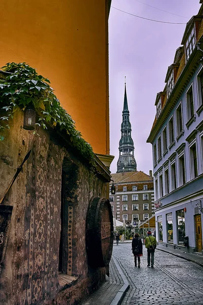 Antigua calle medieval por la noche con la iglesia luterana de San Pedro en Riga, Letonia en el fondo — Foto de Stock