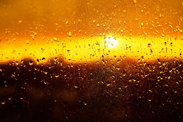 Krople deszczu tekstury na szyby z wspaniały kolorowy pomarańczowy bursztynu zachód światło Abstrakcja niewyraźne gród skyline bokeh tła. Nieostrość. — Zdjęcie stockowe