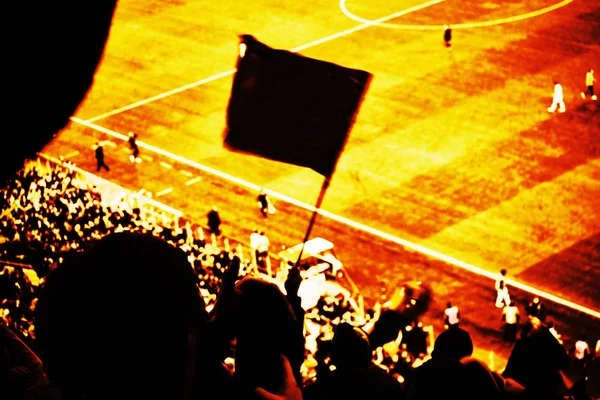 Os fãs de futebol torcem seu time de futebol marcar gol com bandeiras, bandeiras e lenços no estádio. Vista tonificada vermelha e amarela — Fotografia de Stock