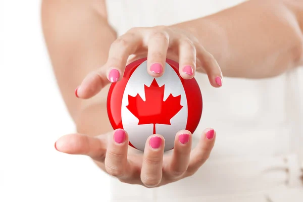 Dwie ręce kobieta ochrona flagi kanadyjskiej ziemi glob kuli. — Zdjęcie stockowe
