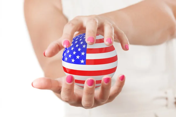 Dos manos de mujer protegiendo la bandera de EE. UU. Esfera globo terrestre . — Foto de Stock