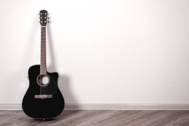 Kopya alanı ile boş bir odada siyah klasik akustik gitar