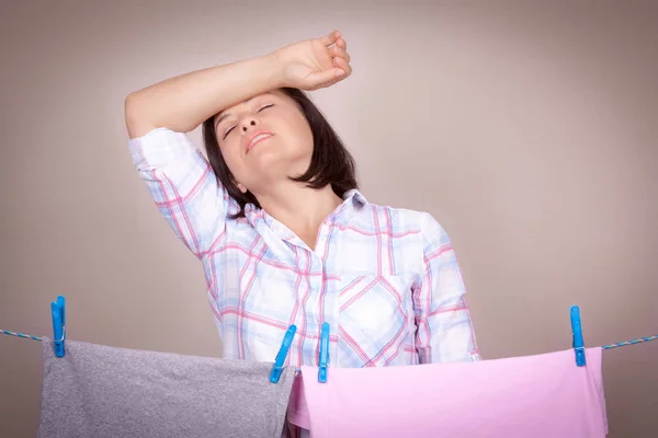 Mujer atractiva cansada colgando paño limpio húmedo para secar en la ropa — Foto de Stock