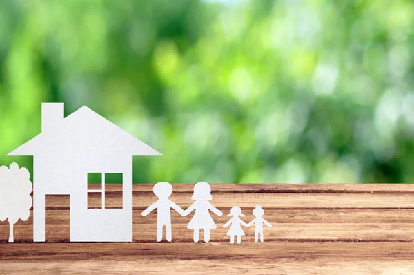 Paper family on wooden table with garden bokeh outdoor theme bac