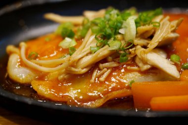 Kırmızı biber soslu Pangasius balık bifteği, siyah tabakta mantar ve sebze, makro odaklı..