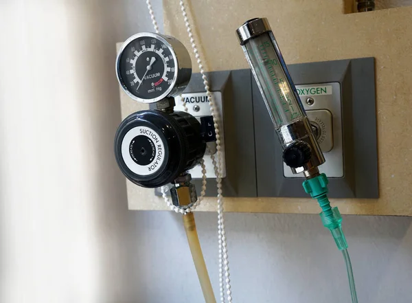 Oda hastanesi veya kliniğinin duvarındaki prize elektrik süpürgesi ve oksijen basıncı ölçüm cihazı takılı..