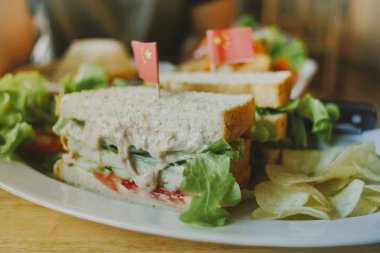 Parlak ışıkta kırsal bir masada bir kulüp sandviçi.